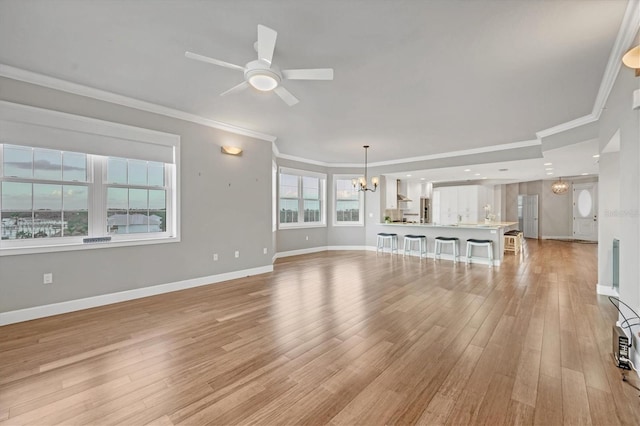 unfurnished living room featuring crown molding, ceiling fan with notable chandelier, and light wood-type flooring