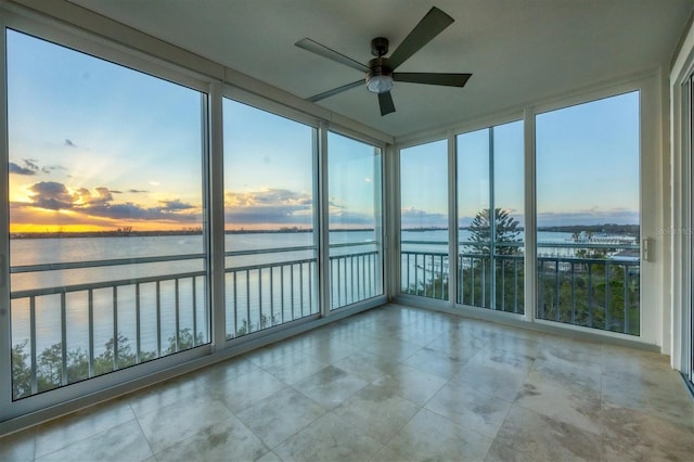 unfurnished sunroom with ceiling fan and a water view