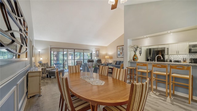 dining space with high vaulted ceiling, light wood-type flooring, and ceiling fan