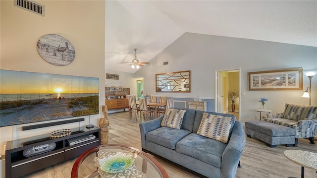 living room featuring light hardwood / wood-style flooring, high vaulted ceiling, and ceiling fan