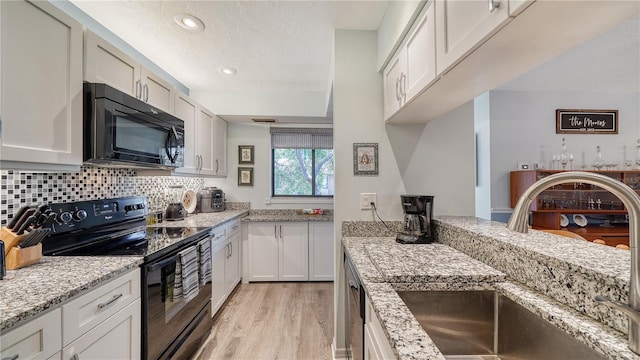 kitchen featuring light hardwood / wood-style flooring, black appliances, sink, and white cabinets