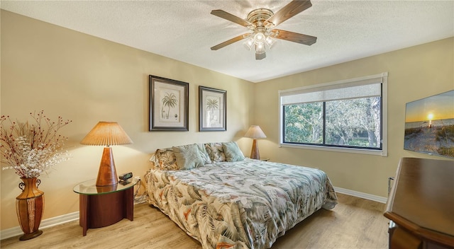 bedroom featuring light hardwood / wood-style flooring, a textured ceiling, and ceiling fan