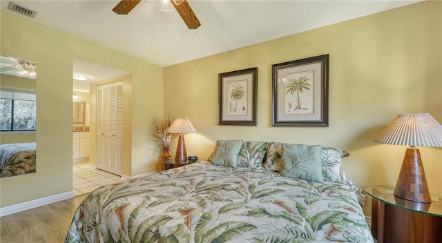 bedroom with a closet, ensuite bath, light wood-type flooring, a textured ceiling, and ceiling fan