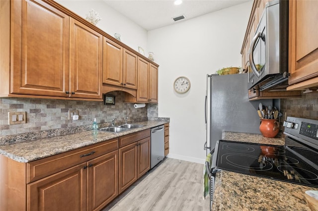 kitchen featuring stainless steel appliances, sink, light wood-type flooring, and light stone counters