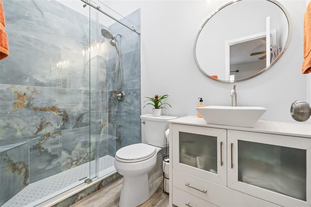 bathroom featuring hardwood / wood-style flooring, a shower with door, vanity, and toilet