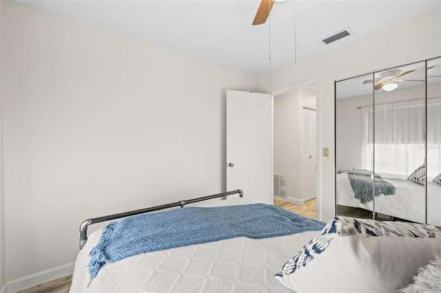 bedroom with light wood-type flooring, ceiling fan, and a closet