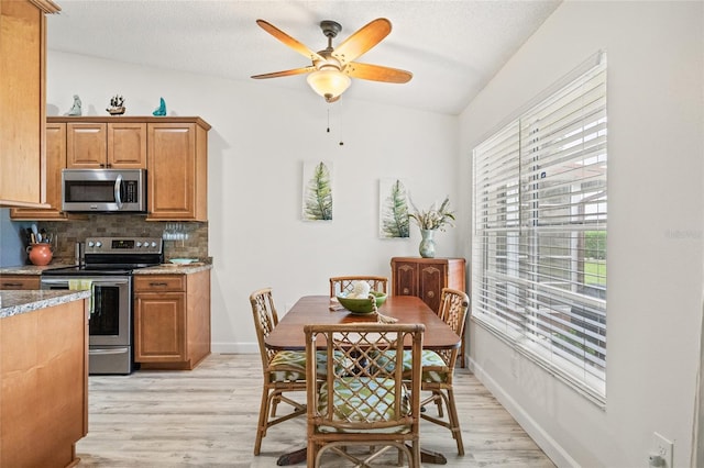 dining area with light hardwood / wood-style flooring, ceiling fan, and vaulted ceiling