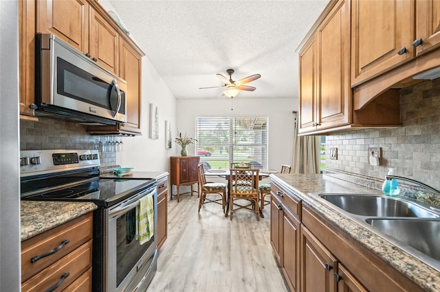 kitchen with light hardwood / wood-style floors, a textured ceiling, sink, backsplash, and appliances with stainless steel finishes