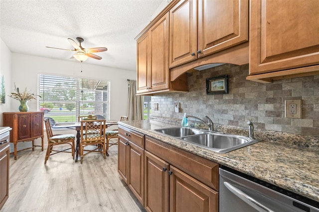 kitchen with a textured ceiling, sink, light hardwood / wood-style floors, stainless steel dishwasher, and ceiling fan