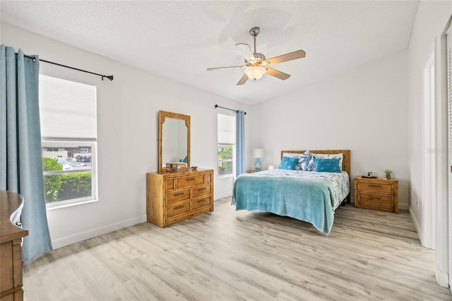 bedroom featuring light hardwood / wood-style floors, ceiling fan, multiple windows, and a textured ceiling