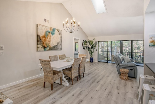 dining space with light hardwood / wood-style floors, an inviting chandelier, and high vaulted ceiling