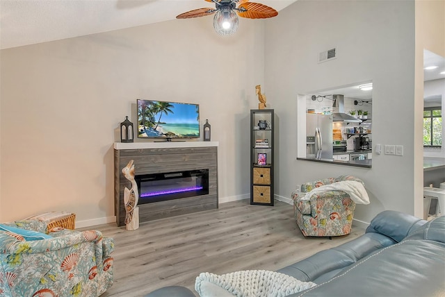 living room featuring ceiling fan, high vaulted ceiling, and light wood-type flooring