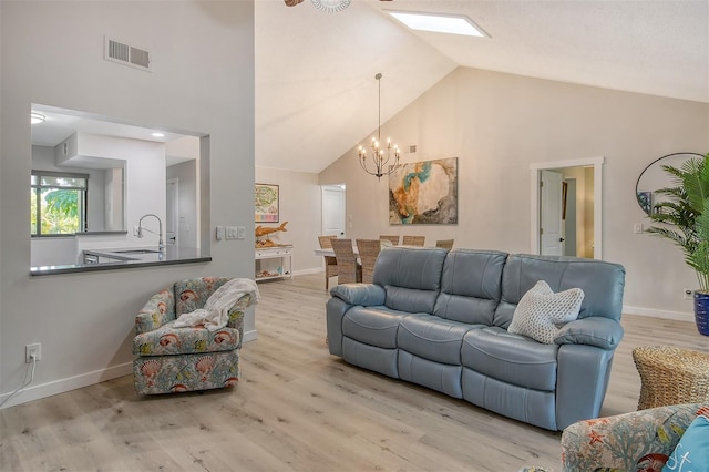 living room with sink, a chandelier, high vaulted ceiling, and light hardwood / wood-style floors