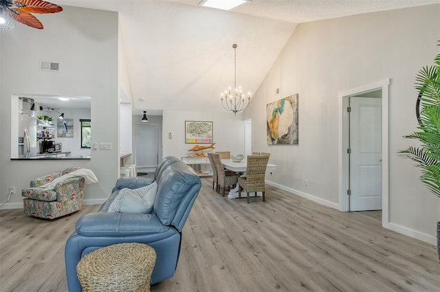 living room with a textured ceiling, ceiling fan with notable chandelier, high vaulted ceiling, and light hardwood / wood-style floors