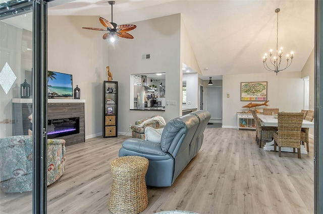 living room featuring light hardwood / wood-style floors, high vaulted ceiling, and ceiling fan with notable chandelier