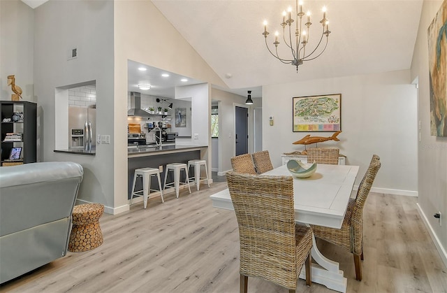 dining space featuring high vaulted ceiling, light hardwood / wood-style flooring, and an inviting chandelier