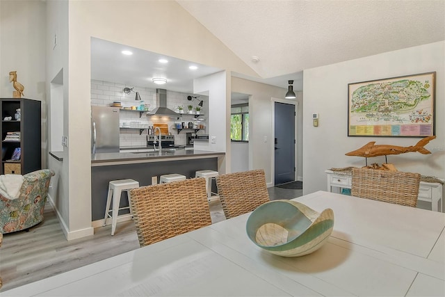 dining space featuring lofted ceiling, hardwood / wood-style floors, a textured ceiling, and sink