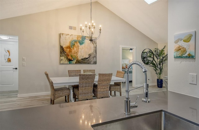 dining space featuring high vaulted ceiling, wood-type flooring, sink, and ceiling fan with notable chandelier