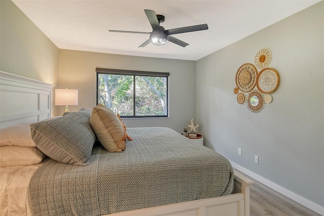 bedroom featuring light hardwood / wood-style floors, a textured ceiling, and ceiling fan