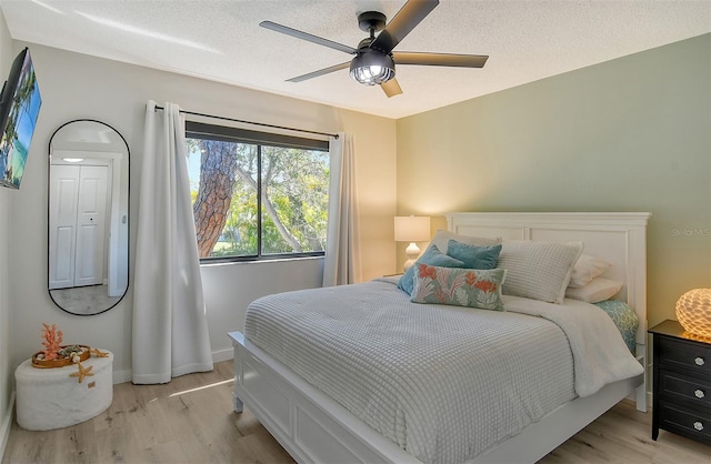 bedroom with a textured ceiling, light wood-type flooring, and ceiling fan