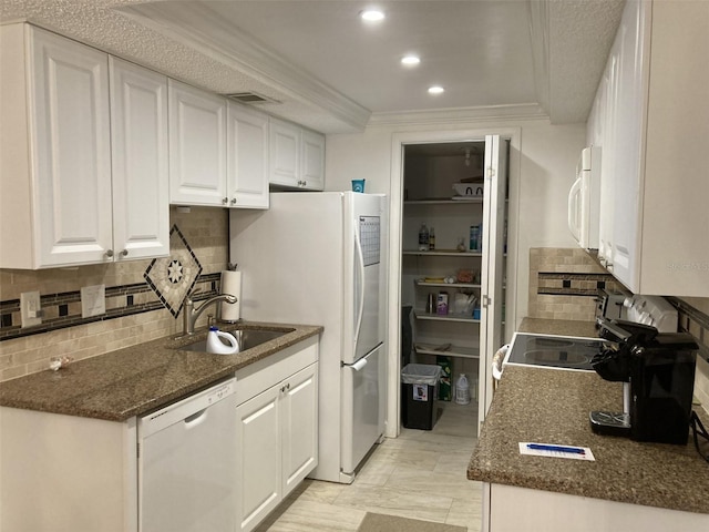 kitchen featuring white cabinets, sink, dark stone counters, and white appliances