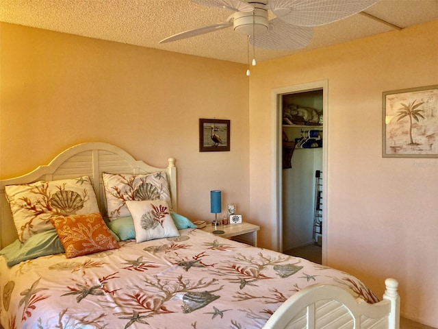 bedroom with a closet, ceiling fan, a textured ceiling, and a walk in closet