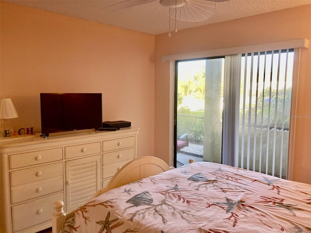 bedroom with ceiling fan, access to outside, and a textured ceiling