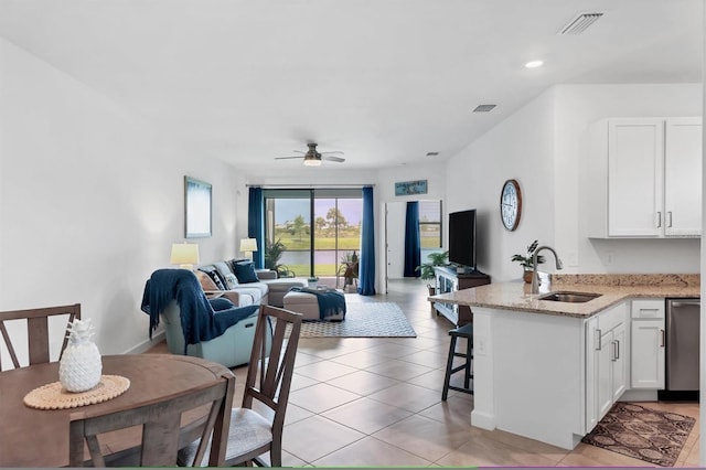 kitchen with white cabinetry, light stone countertops, sink, a breakfast bar area, and ceiling fan