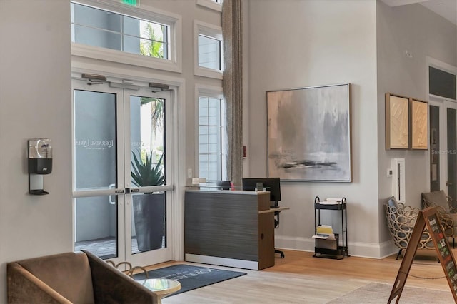 doorway to outside with a towering ceiling and light hardwood / wood-style flooring