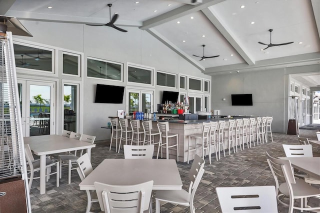 interior space with ceiling fan, beamed ceiling, bar, and high vaulted ceiling