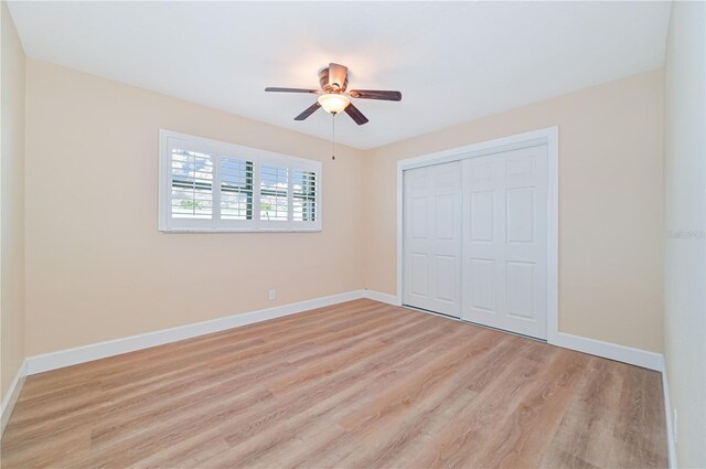 unfurnished bedroom featuring a closet, light hardwood / wood-style floors, and ceiling fan