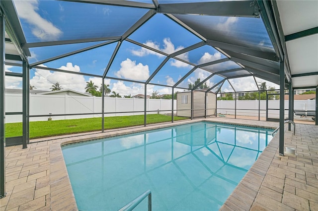 view of swimming pool with glass enclosure, a yard, a patio, and a storage shed