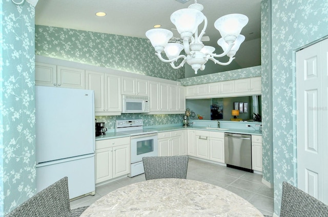 kitchen featuring an inviting chandelier, light tile patterned flooring, decorative light fixtures, white appliances, and white cabinets