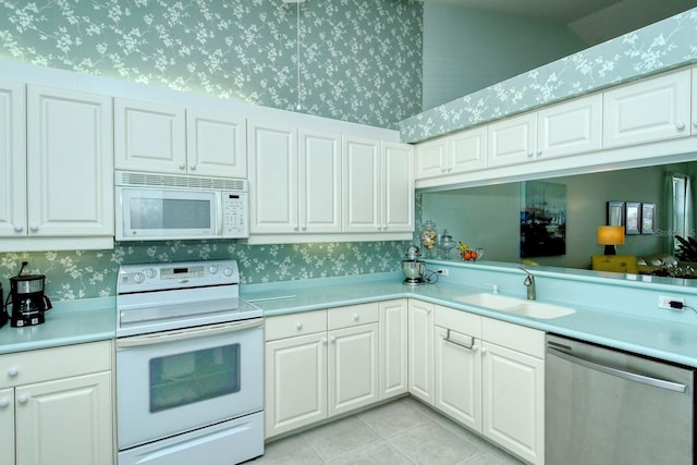 kitchen featuring white cabinetry, sink, kitchen peninsula, white appliances, and light tile patterned floors