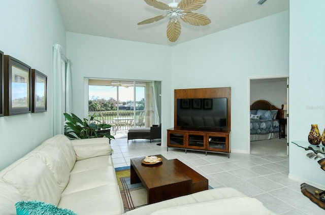 tiled living room with ceiling fan and a high ceiling