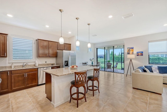 kitchen with a wealth of natural light, hanging light fixtures, a kitchen island, and stainless steel appliances