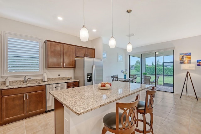 kitchen with appliances with stainless steel finishes, sink, pendant lighting, a center island, and plenty of natural light