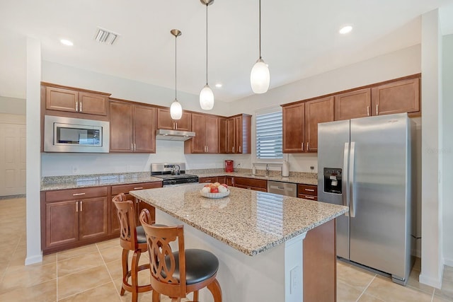 kitchen with light stone countertops, a breakfast bar, stainless steel appliances, a center island, and hanging light fixtures