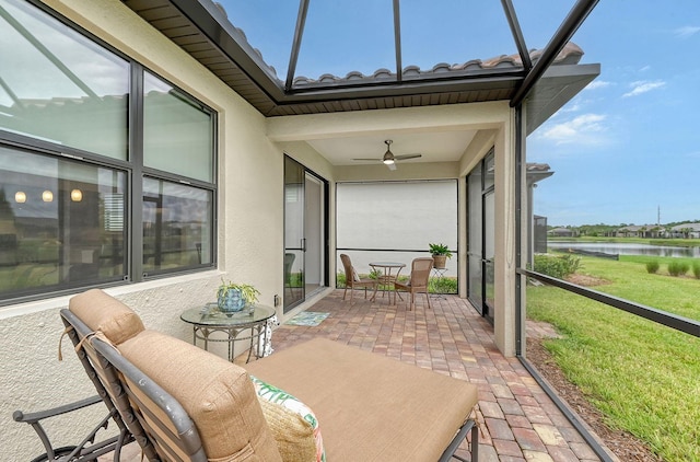 sunroom / solarium featuring ceiling fan and a water view