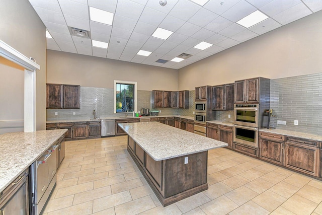 kitchen with a kitchen island, light stone counters, and a high ceiling