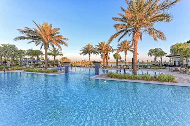 pool at dusk featuring a water view