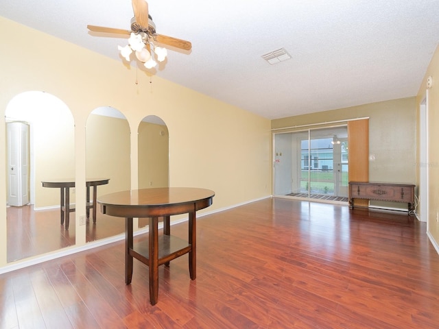 dining area with dark wood-type flooring, ceiling fan, and a textured ceiling