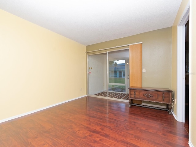 unfurnished room with a textured ceiling and dark hardwood / wood-style floors