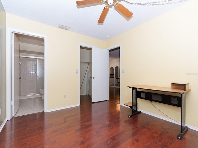 unfurnished bedroom with a closet, a spacious closet, dark hardwood / wood-style flooring, ceiling fan, and ensuite bathroom