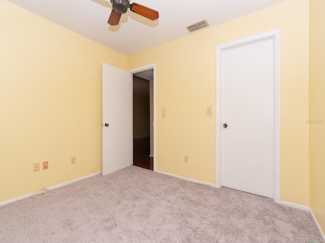 empty room featuring a textured ceiling, light carpet, and ceiling fan