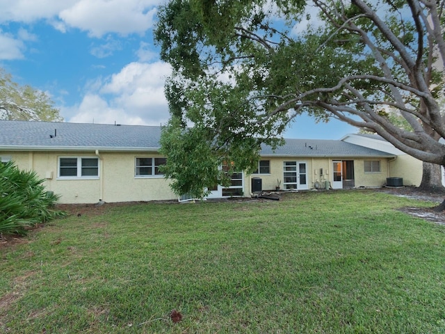 back of property featuring cooling unit and a yard