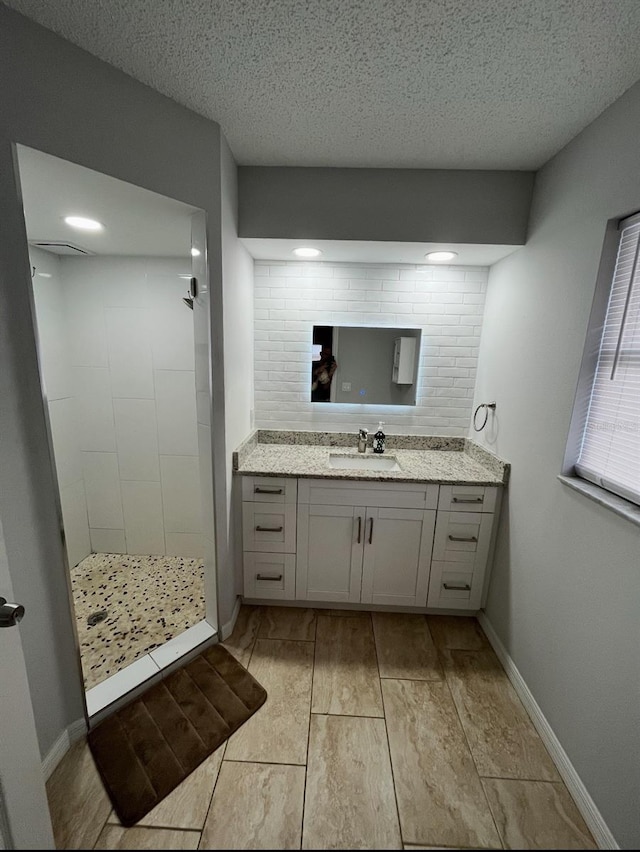 bathroom with decorative backsplash, a shower, vanity, and a textured ceiling