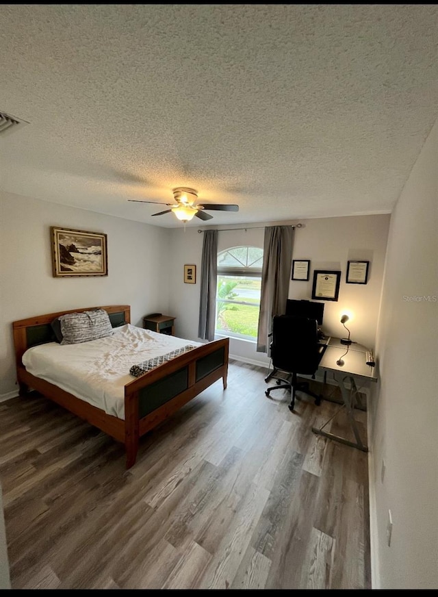 bedroom with ceiling fan, hardwood / wood-style floors, and a textured ceiling