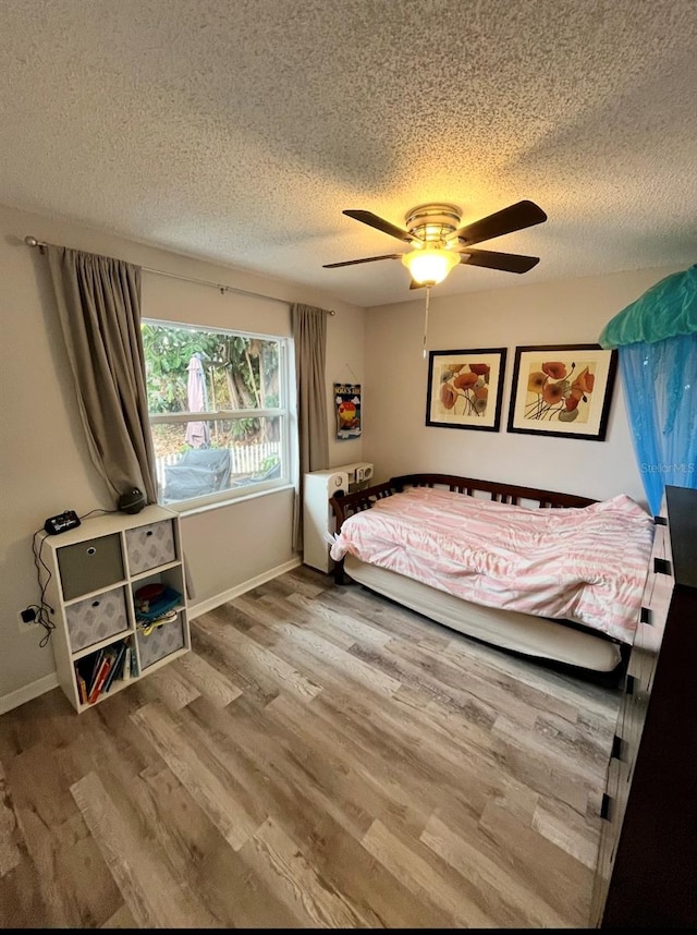 bedroom with wood-type flooring, a textured ceiling, and ceiling fan