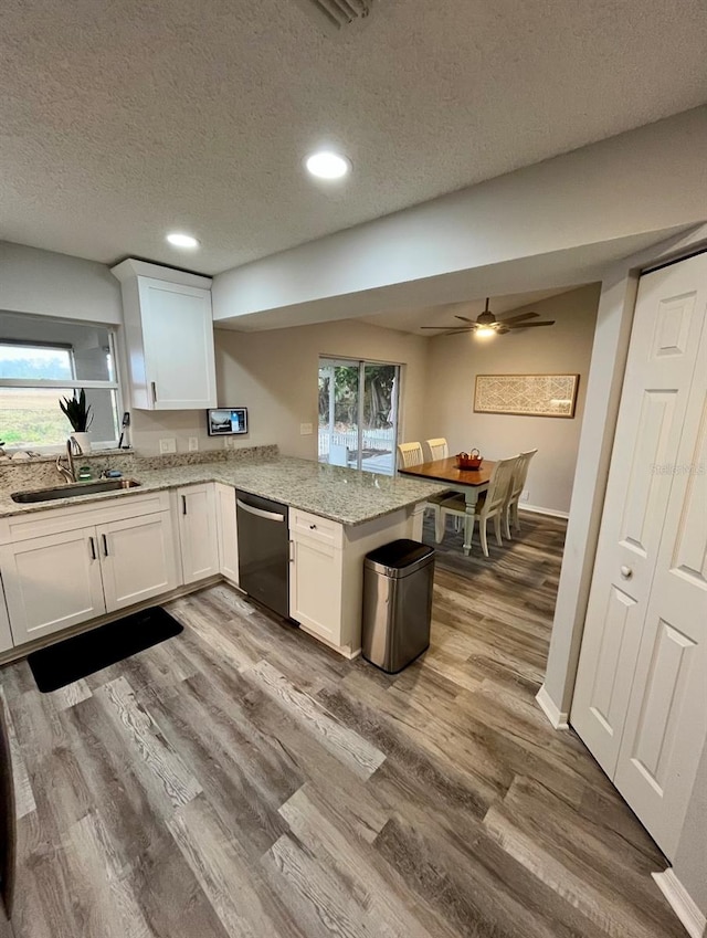 kitchen featuring kitchen peninsula, white cabinetry, stainless steel dishwasher, and sink